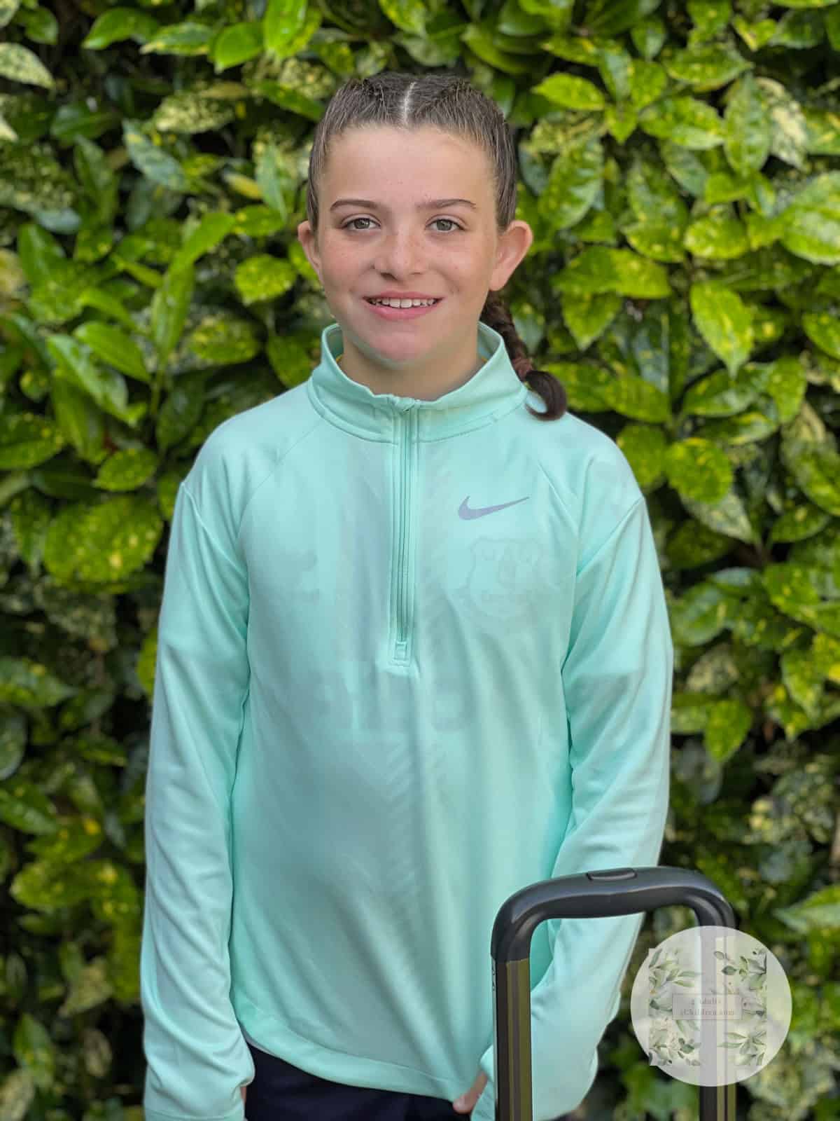 11 year old girl with plaits stood next to a suitcase
