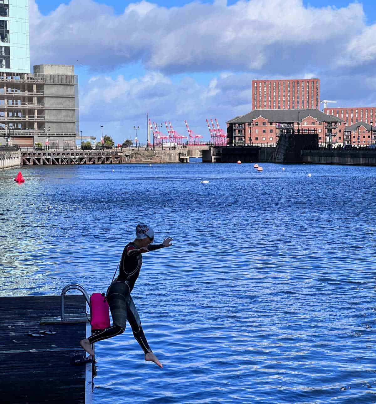 teenage girl jumping into open water feet first in Liverpool docks