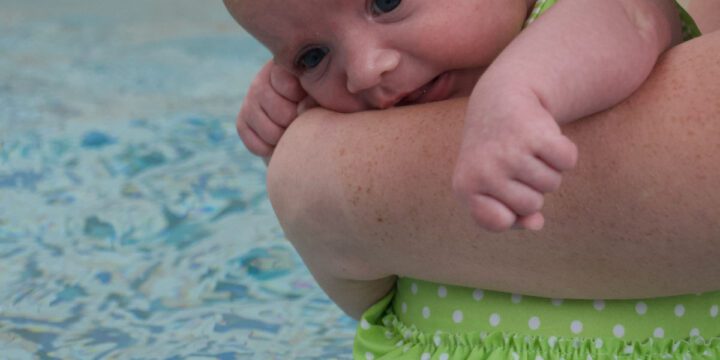 Baby being held near a swimming pool