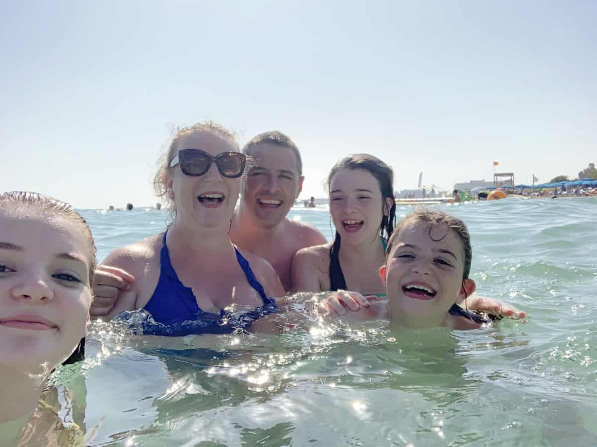 5 families members (mum, dad and 3 daughters) swimming in the sea and laughing