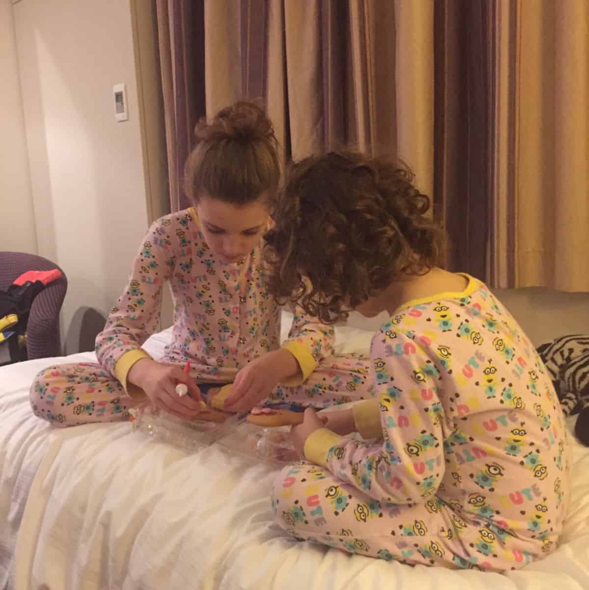 2 girls on a bed in matching onesies concentrating hard on a puzzle