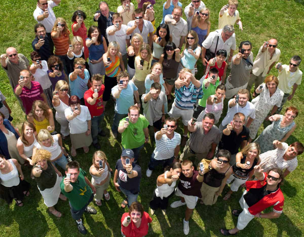 a group of sixth form college students stood in a field looking up to the sky with their phones and thumbs aloft